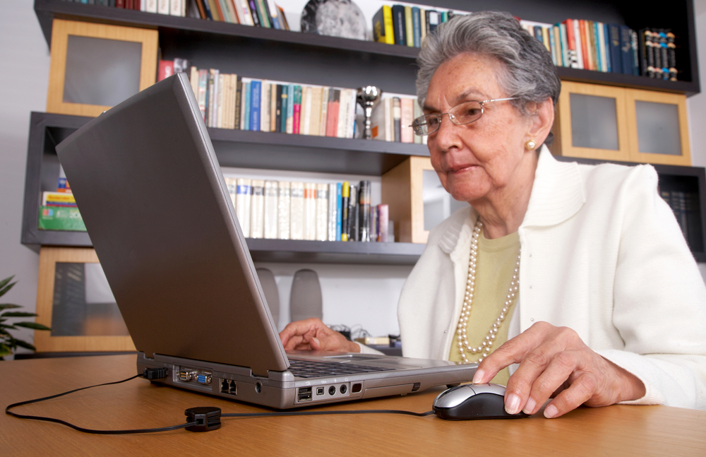 eldery woman on a laptop at home reading the screen